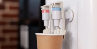 close up disposable cup water cooler startup office water dispenser with hot cold faucet used refreshment beverage space purified mineral water gallon