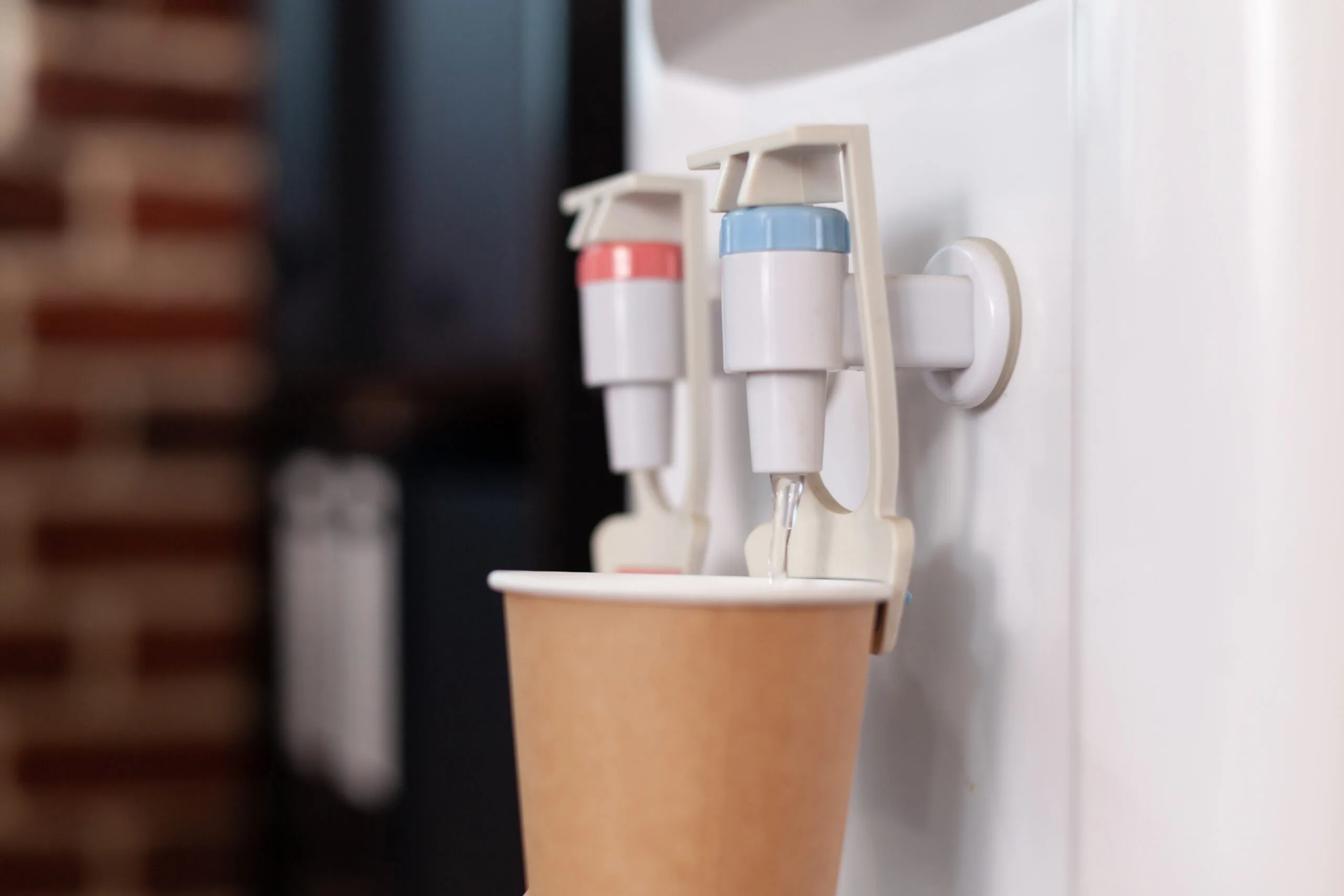 close up disposable cup water cooler startup office water dispenser with hot cold faucet used refreshment beverage space purified mineral water gallon scaled